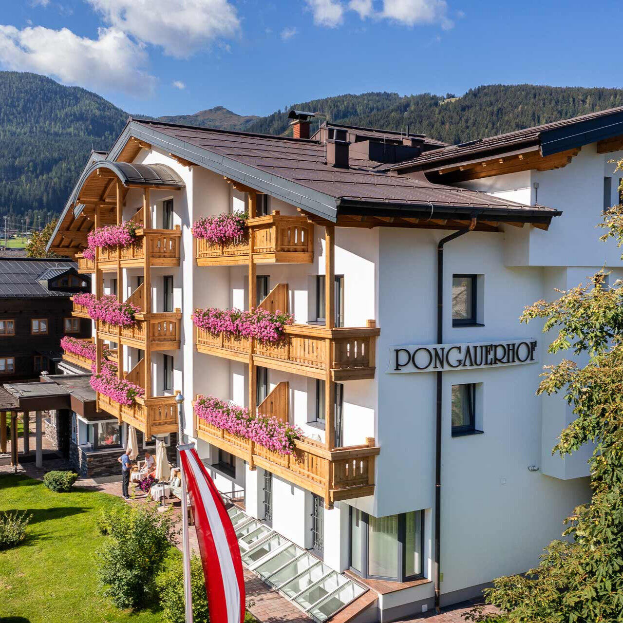 Außenansicht des 4-Sterne-Hotels Pongauerhof in Flachau mit Blumenbalkonen